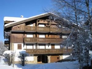 un grande edificio in legno con una terrazza nella neve di Résidence Palmes D'or - Studio pour 4 Personnes 784 a Les Contamines-Montjoie
