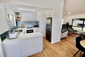 a white kitchen with a refrigerator and a living room at Beach House with Sea Views and a Large Backyard in Devonport