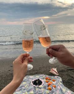 dos personas sosteniendo copas de champán en la playa en Rooming House en Playa Blanca