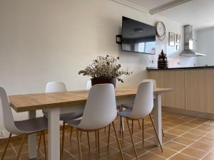 une salle à manger avec une table en bois et des chaises blanches dans l'établissement Alojamiento Rural El Castillo, à Agoncillo