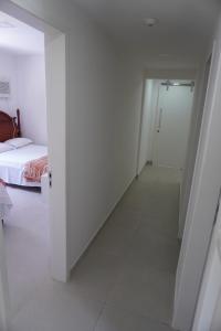 einen weißen Flur mit einem Bett und einer Tür in der Unterkunft Casa do Sol na Reserva do Paiva in Cabo de Santo Agostinho