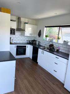 a kitchen with white cabinets and black counter tops at Double Bedroom with Private Bathroom in Porirua