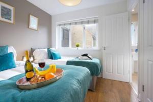 a room with two beds with a tray of fruit and wine at Forthill House - Close to City Centre - Free Parking, Super-Fast Wifi and Smart TV with Netflix by Yoko Property in Milton Keynes