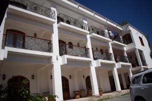 a white building with balconies and a car parked in front at La Ramada in Cafayate