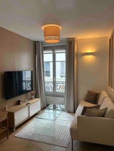 a living room with a couch and a television at Cocooning & Cosy Apartment in Center Paris 17 in Paris