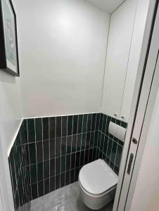 a small bathroom with a toilet and green tiles at Cocooning & Cosy Apartment in Center Paris 17 in Paris