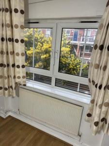 a room with two windows with curtains and a radiator at one bedroom apartment in Tower Bridge road in London