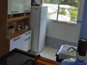 une cuisine avec un réfrigérateur blanc et une fenêtre dans l'établissement Apartamento com Vista para Mar, à Piúma