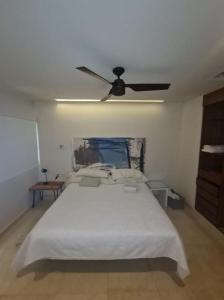 a bedroom with a white bed and a ceiling fan at Moderno departamento en Playa del Carmen in Playa del Carmen