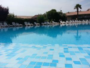 a large swimming pool with chairs and blue water at Lago Residence in Desenzano del Garda