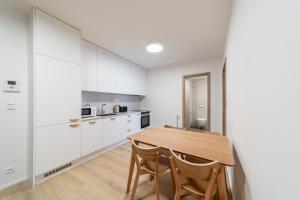 a kitchen with white cabinets and a wooden table at Residence Mozaika in Prague