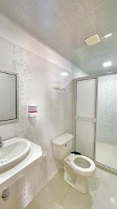 a white bathroom with a toilet and a sink at Hotel BJ Curumani in Curumaní