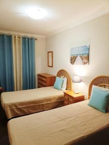 two beds in a hotel room with blue curtains at Sesimbra Flat in Sesimbra