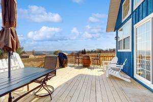 eine Holzterrasse mit einer Bank und einem blauen Haus in der Unterkunft Vineyard Sanctuary in Penn Yan