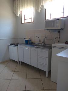 a white kitchen with a sink and a microwave at Wana casa 2 Requinte e conforto in Sao Jose do Rio Preto
