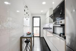 a white kitchen with a table and a microwave at Ven descansa y conoce Málaga in Málaga