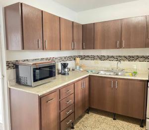 a kitchen with wooden cabinets and a microwave at Nela’s Beach House in Arecibo