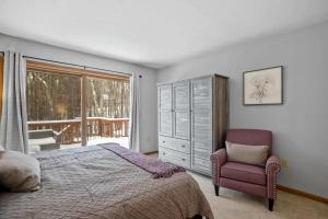 a bedroom with a bed and a chair and a window at Gilford Family Retreat in Gilford