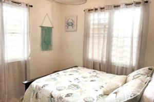 a bedroom with a bed and two windows at Nela’s Beach House in Arecibo