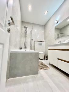 ein weißes Badezimmer mit einer Badewanne und einem Waschbecken in der Unterkunft Apartament Chisinau in Chişinău