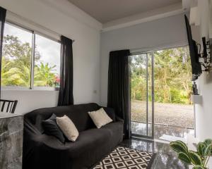 uma sala de estar com um sofá preto e janelas grandes em Villa el Descanso em San Pedro