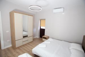 a white bedroom with a bed and a mirror at The Met Apartments in Durrës
