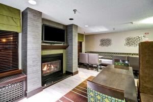 a living room with a fireplace and a television at Hampton Inn State College in State College