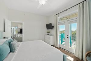 Habitación blanca con cama y balcón. en Coastal Vista - Walk to Emerald Isle Beach!, en Emerald Isle