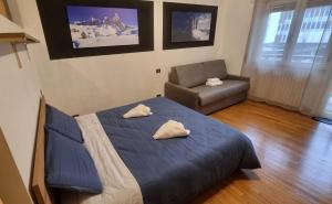 1 dormitorio con 1 cama azul y 1 silla en Studio Apartment Ariston in centro a Cortina en Cortina dʼAmpezzo