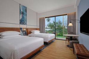 a hotel room with two beds and a large window at Four Points by Sheraton Bintan, Lagoi Bay in Lagoi