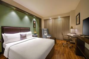 a hotel room with a large bed and a desk at Hampton by Hilton Vadodara-Alkapuri in Vadodara