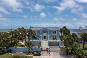 a large blue house with palm trees at Gone Coastal - Oceanfront Home with a Hotub in Ponte Vedra Beach