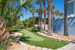 un campo de golf con palmeras junto a una casa en Gone Coastal - Oceanfront Home with a Hotub, en Ponte Vedra Beach