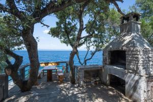 uma lareira de pedra com uma mesa de piquenique e o oceano em Seaside secluded apartments Cove Vela Borova, Korcula - 15062 em Prizba