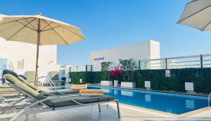 a pool with chairs and an umbrella next to a pool at Hampton By Hilton Dubai Al Barsha in Dubai