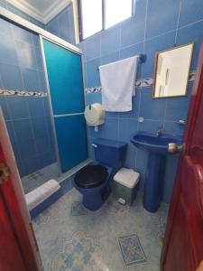 Baño azul con aseo y lavamanos en Hostal Insular, en Puerto Villamil