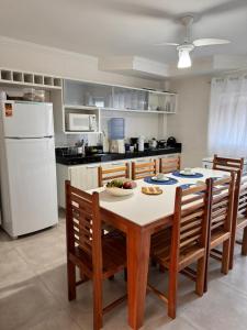 a kitchen with a table and chairs and a white refrigerator at Arraial d Ajuda - Casa Oásis - Residencial Monte das Oliveiras in Porto Seguro