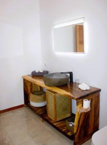 La salle de bains est pourvue d'un comptoir avec un lavabo et un miroir. dans l'établissement Bungalow Tiarii, avec accès direct à une plage privée, à Tevaitoa