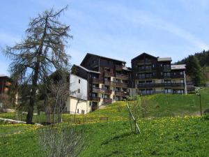 a large building sitting on top of a green hill at Résidence Michailles - Studio pour 4 Personnes 94 in Peisey-Nancroix