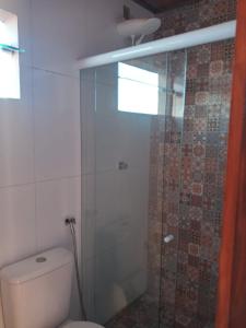 uma casa de banho com um WC e uma cabina de duche em vidro. em Casa taipu de dentro em Maraú