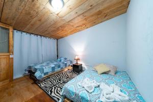 Cabaña rústica en la montaña في Calograma: غرفة نوم بسريرين وسقف خشبي