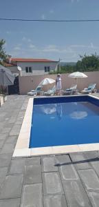 Ein Mann steht neben einem blauen Pool. in der Unterkunft Family friendly house with a swimming pool Imotski, Zagora - 22623 in Imotski