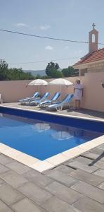 eine Person, die neben einem Pool mit Stühlen und Sonnenschirmen steht in der Unterkunft Family friendly house with a swimming pool Imotski, Zagora - 22623 in Imotski