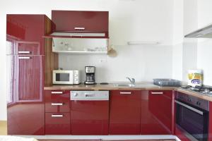 - une cuisine équipée de placards rouges et d'un four micro-ondes dans l'établissement Apartments by the sea Umag - 22628, à Umag