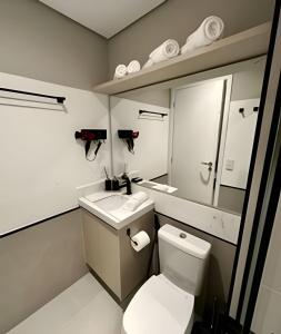 a bathroom with a toilet and a sink and a mirror at Studio C9 de alto padrão in Marília