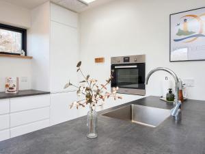 uma cozinha com um lavatório e um vaso com flores em Holiday home Sydals C em Sønderby
