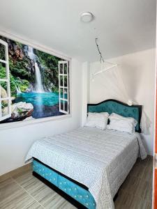 a bedroom with a bed with a waterfall painting on the wall at Hospedaje Don Lalo in Tortuga