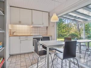 uma cozinha com armários brancos e uma mesa e cadeiras em Holiday home Nexø XX em Neksø