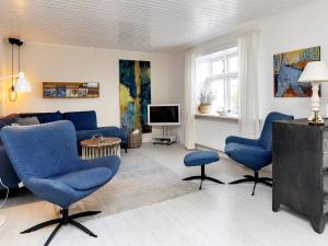 un salon avec des chaises bleues et une télévision dans l'établissement Holiday home Læsø XVII, à Læsø