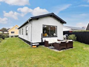 a small white house with a patio and chairs at Holiday home Skagen XL in Skagen